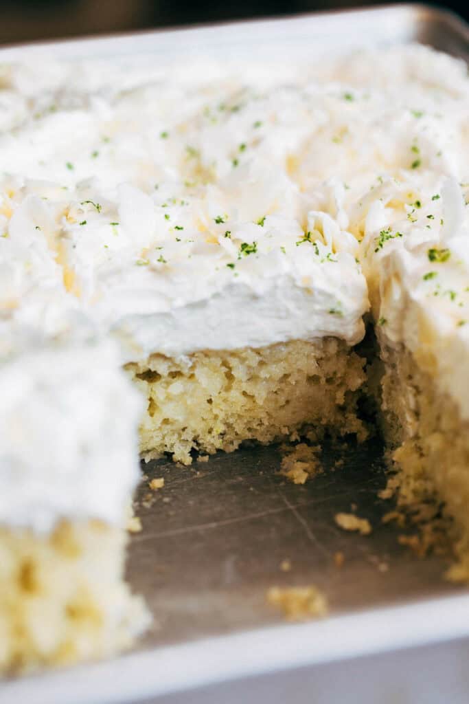 Inside of a sliced lime cake with coconut whipped cream topping.
